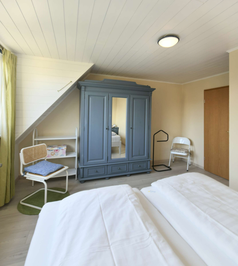 Helles Schlafzimmer mit Doppelbett, großem Kleiderschrank, warmen Farben und gemütlicher Atmosphäre in einer modernen Ferienwohnung.